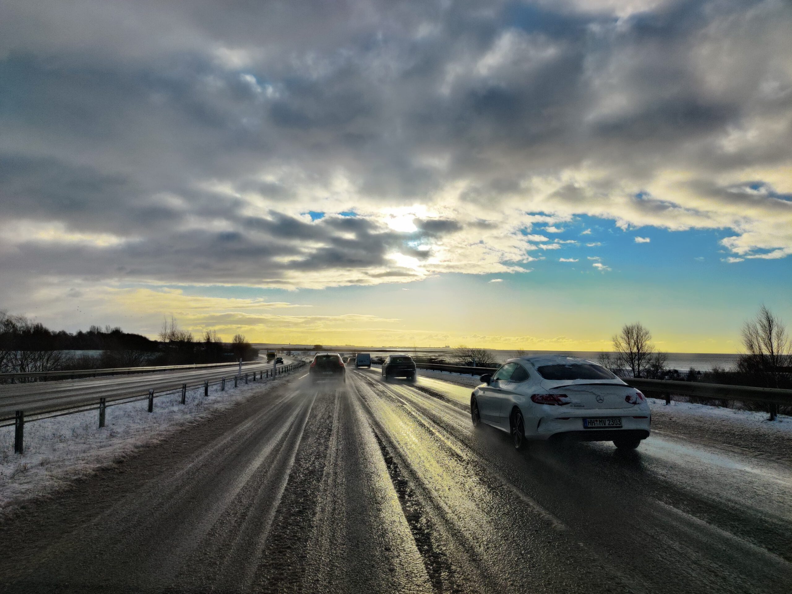 Prachtige lucht boven het water tijdens de terugreis richting Malmö, met het glimmende wegdek op de voorgrond.