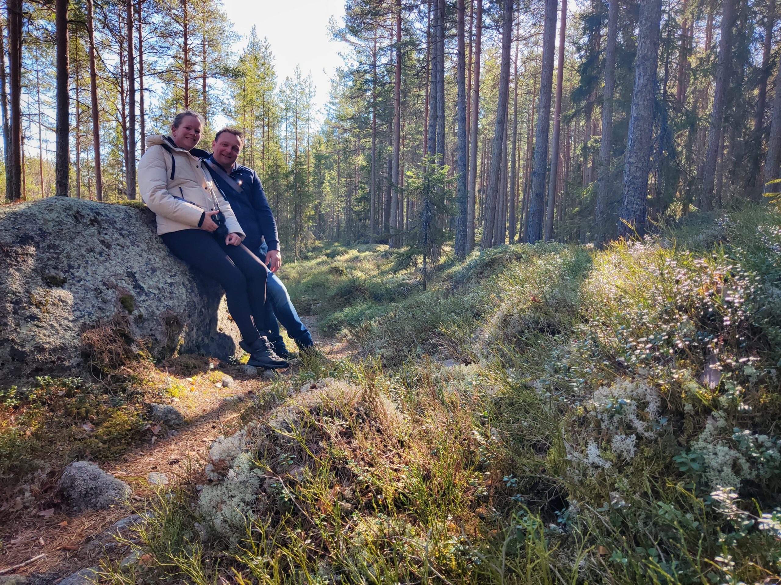 Erik en Patricia rusten uit bij een grote steen tijdens een wandeling door de natuur van Värmland