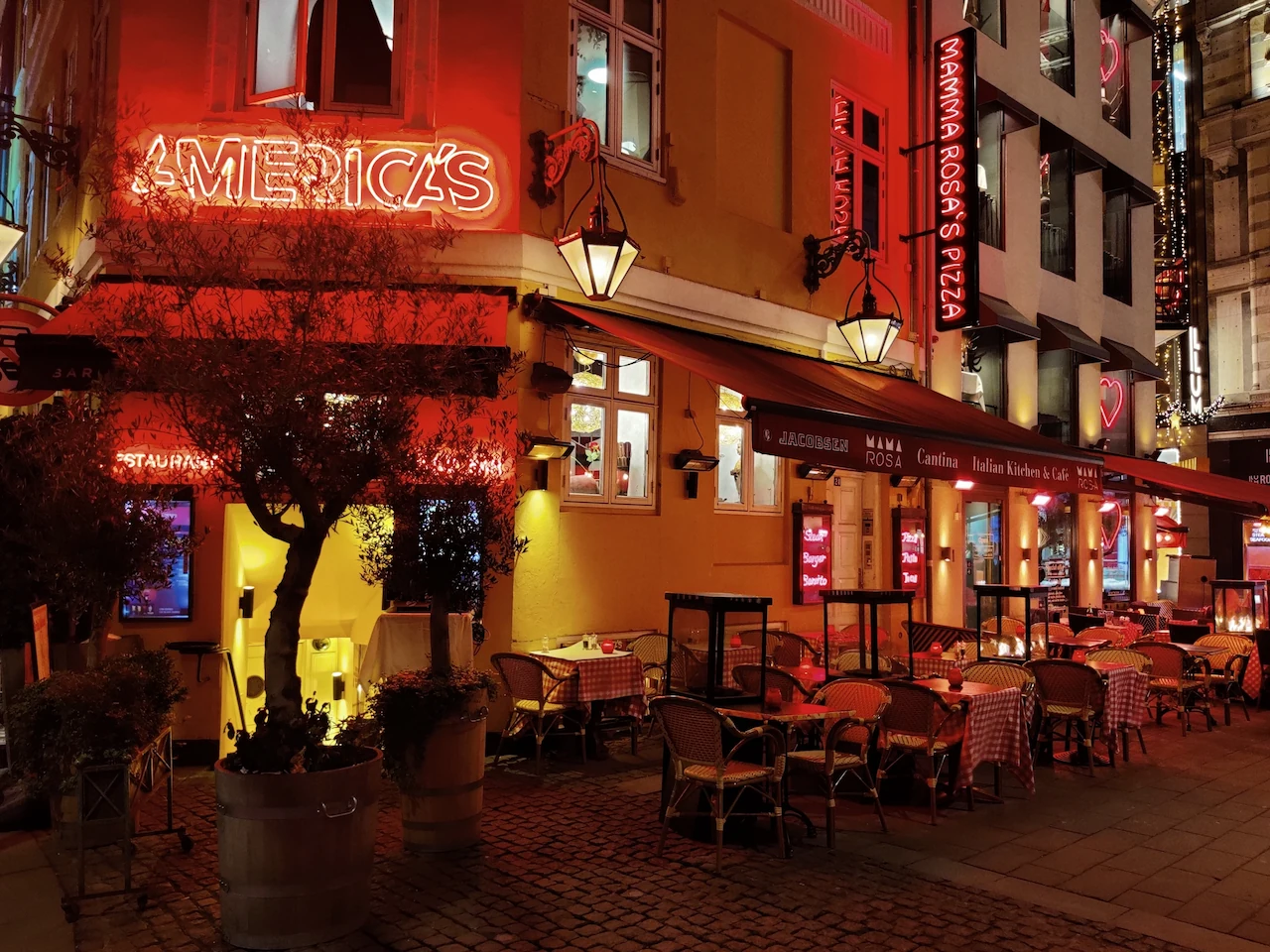 De sfeervol verlichte gevel van restaurant America's Grill in Kopenhagen bij avond.