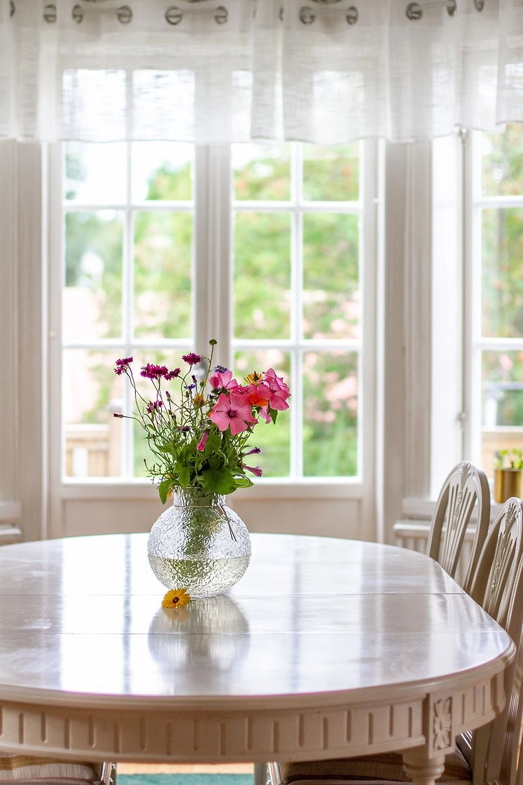 Frisse bloemen op de houten eettafel in de lichte eetkamer van Hus Björken