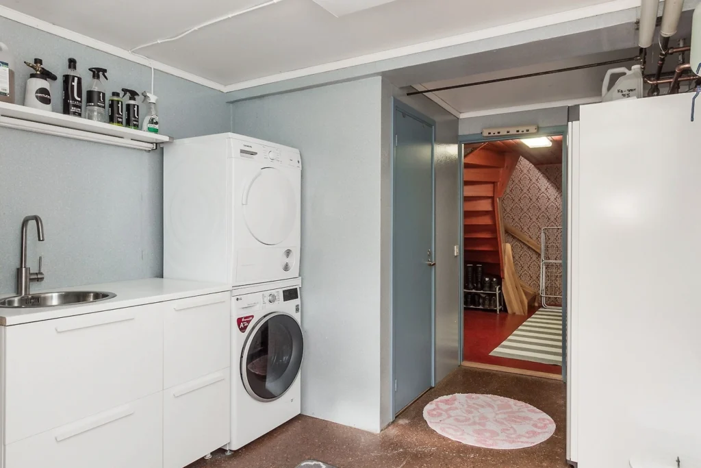 Praktische wasruimte met wasmachine, droger en wasmeubel in Hus Björken