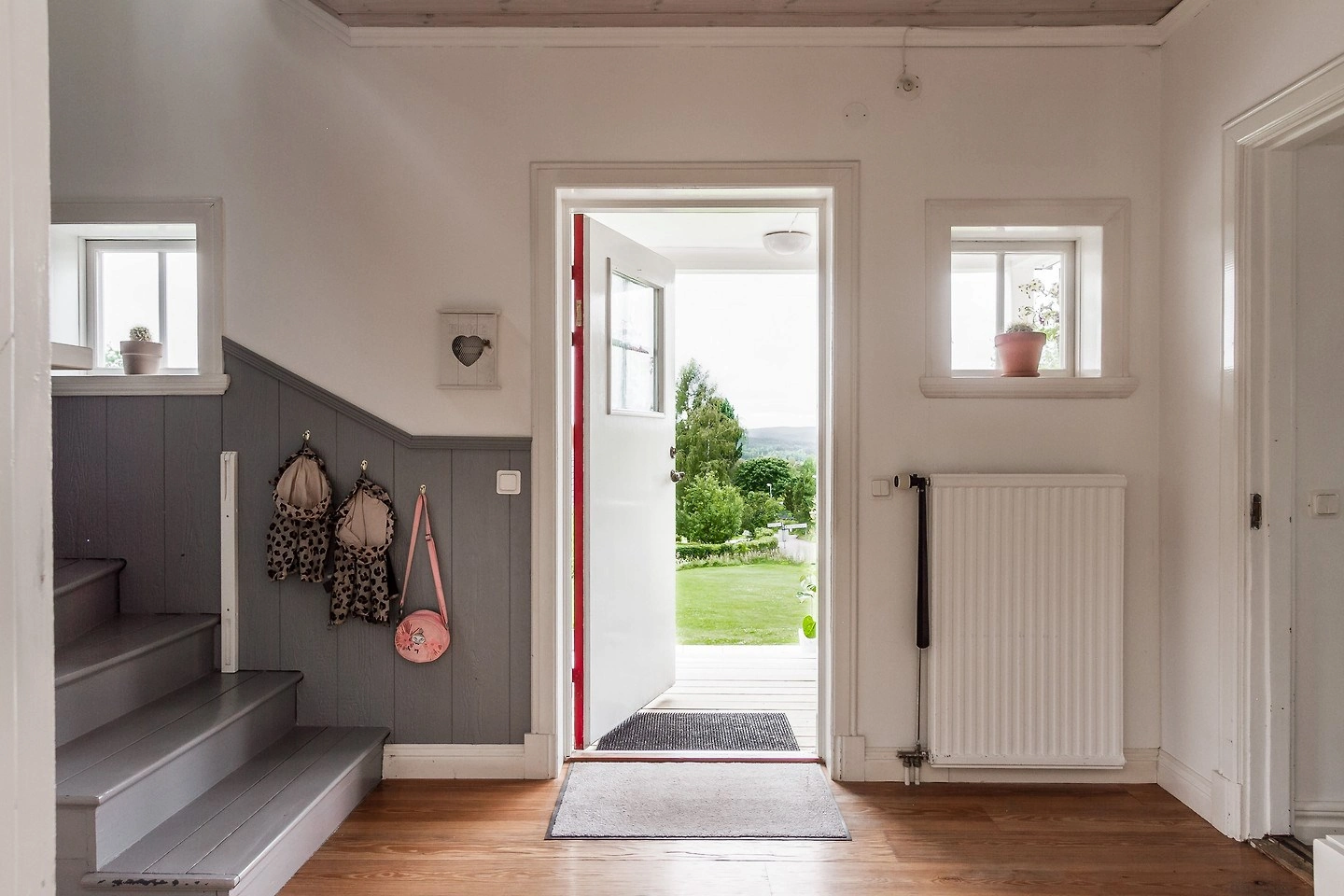 Blik door de openstaande voordeur van Hus Björken op de tuin en de groene omgeving