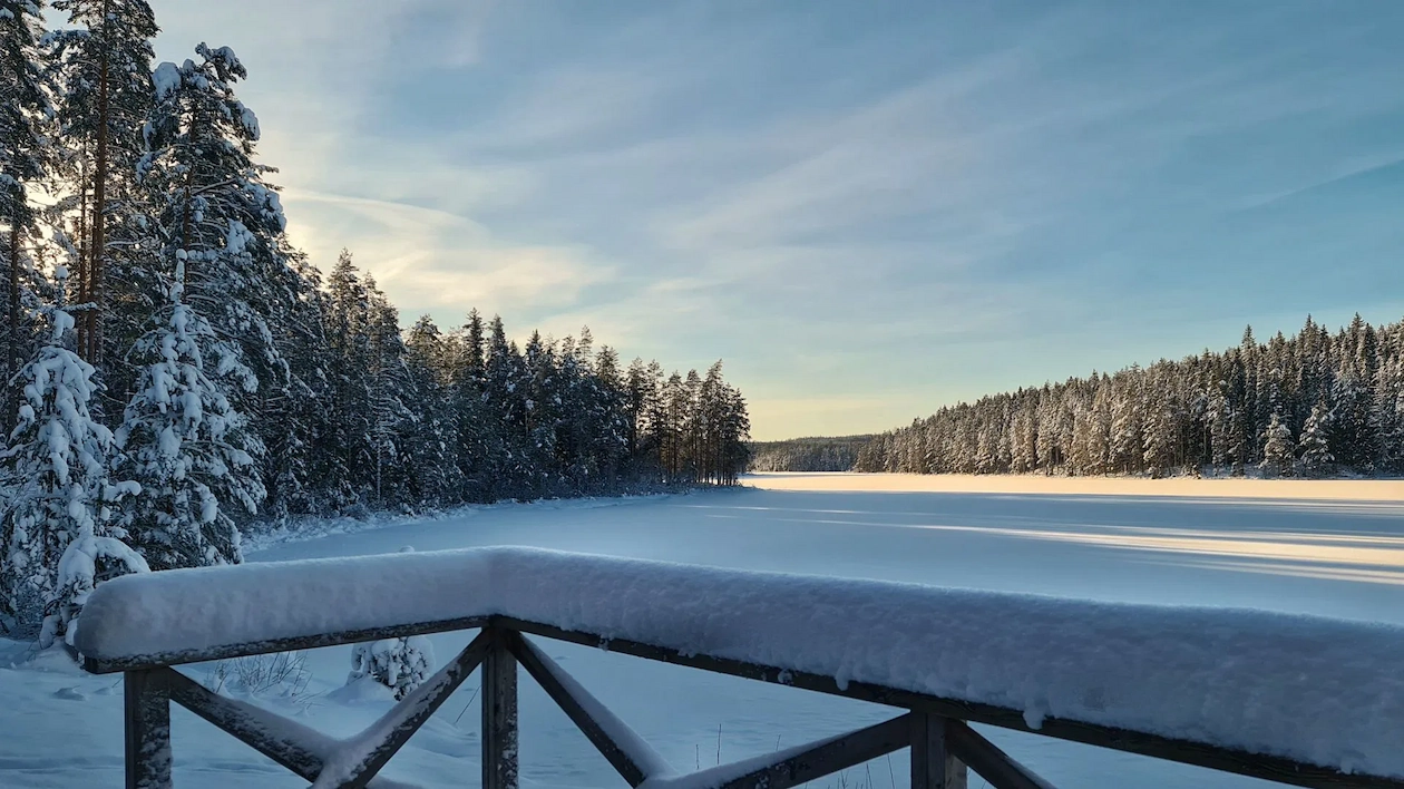 Uitzicht vanaf de besneeuwde steiger op een houtgestookte sauna aan het bevroren Vågsjön meer in Munkfors.